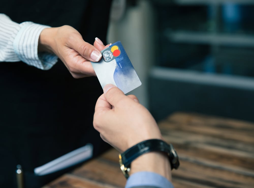 man handing credit card to woman