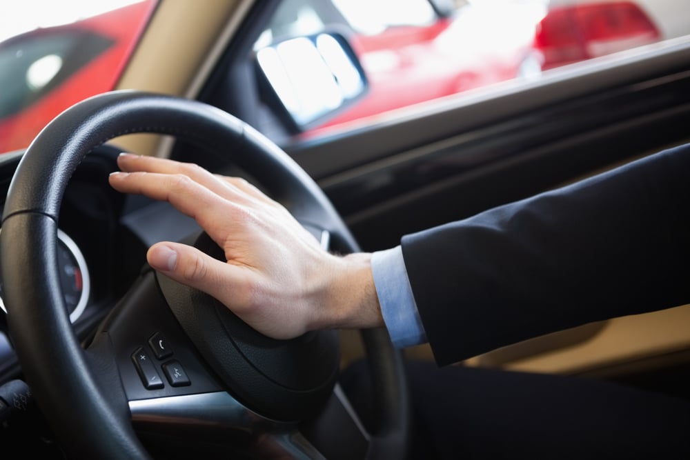 man honking horn at car dealership